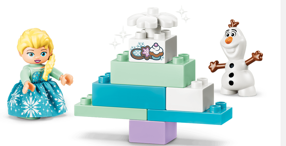 Elsa und Olaf stehen neben einem bunten Bauklotz-Kuchen mit Sternen.