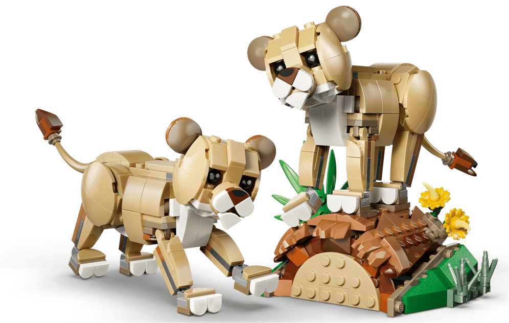 Zwei Lego-Löwen auf einem Felsen mit Pflanzen und Blumen.