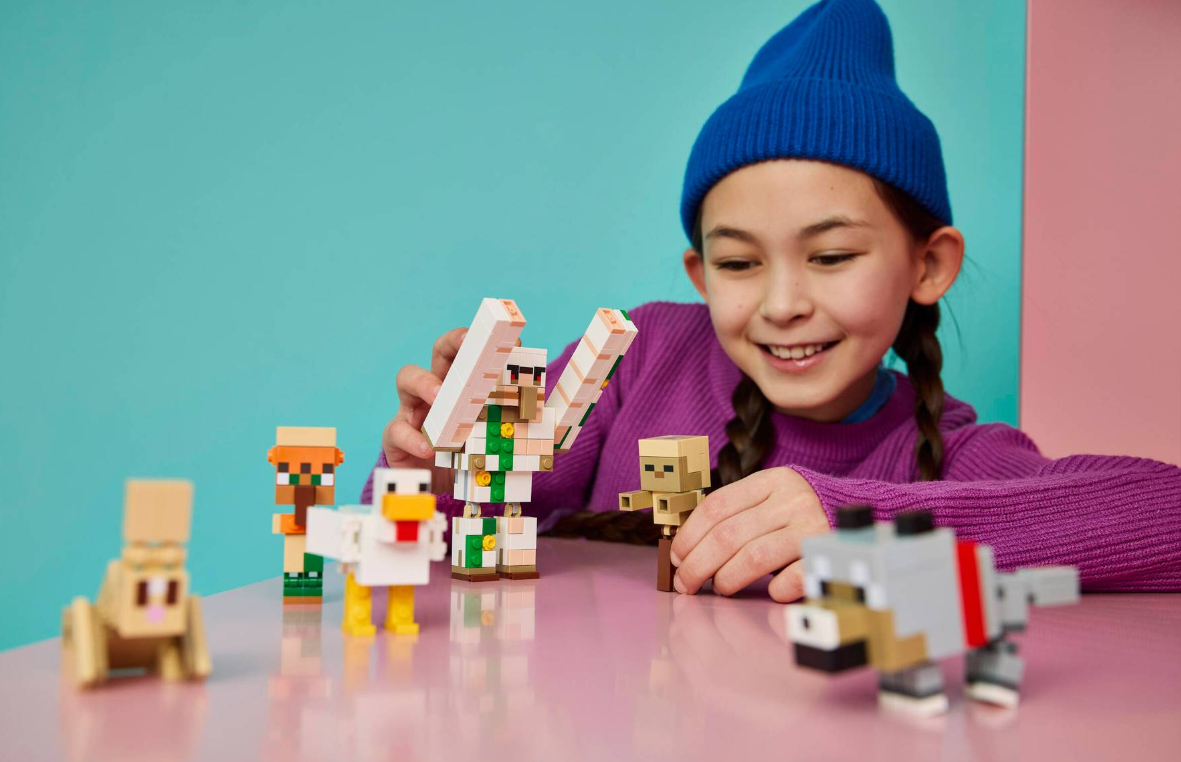 Kind spielt mit Minecraft-Figuren: Henne, Golem, Dorfbewohner, Wolf, Hase.