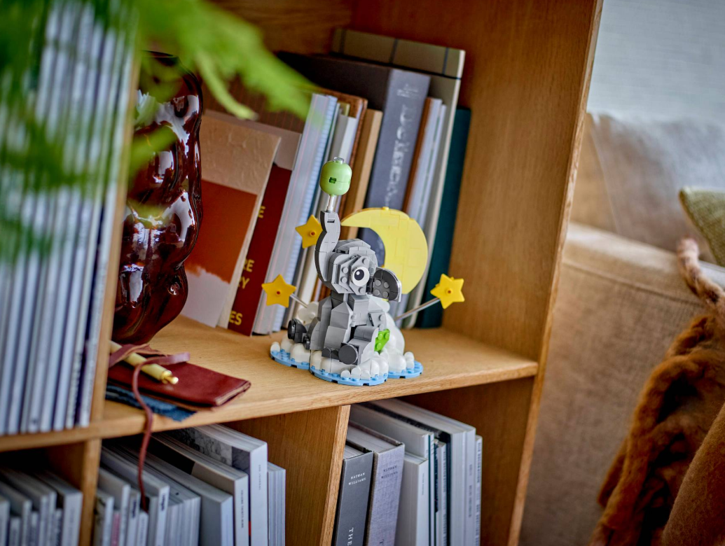 Ein Lego-Elefant sitzt auf Wolken mit Sternen und Mond. Bücherregalhintergrund.