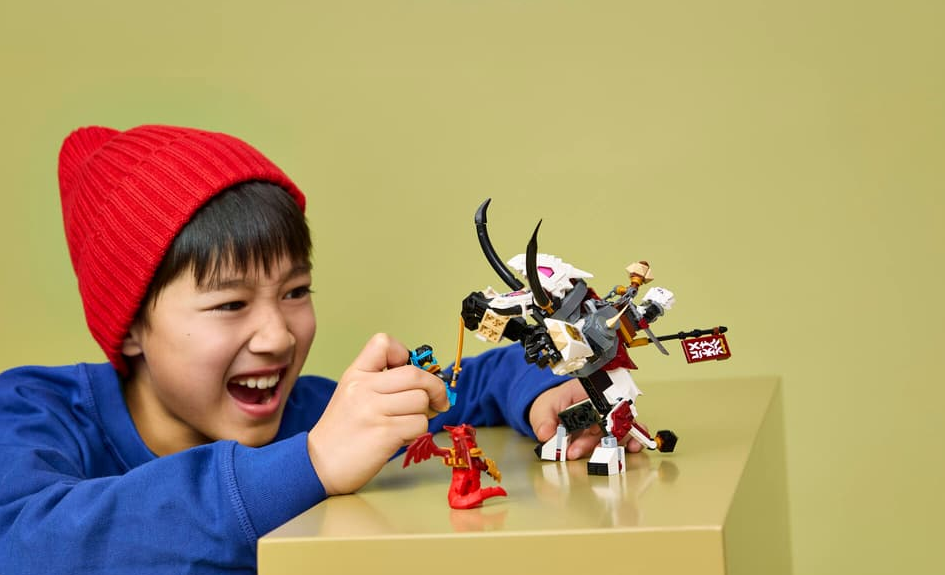 Junge mit roter Mütze spielt mit Lego-Figuren und einem Drachen.