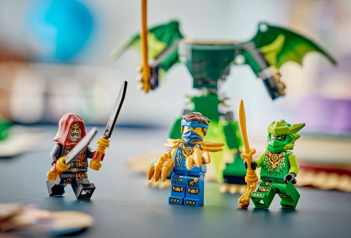 Drei Lego-Ninjas mit Waffen vor einem grünen Drachen.