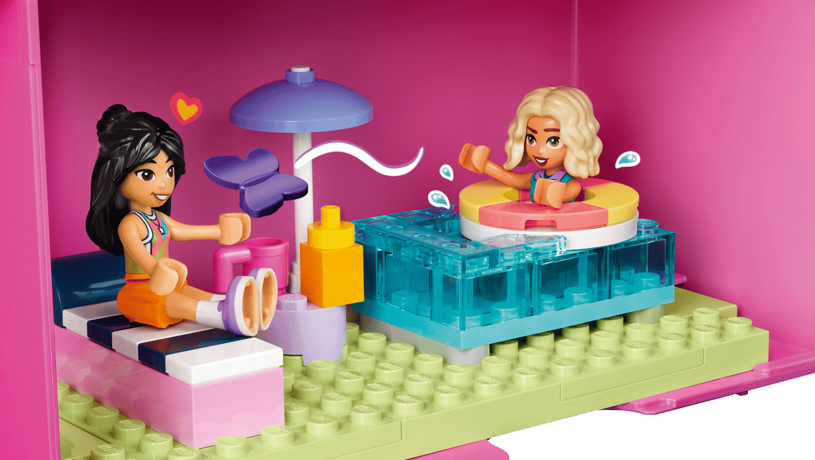 Zwei Lego-Figuren in einem rosa Spielhaus mit Pool, Schmetterling und Blumen.