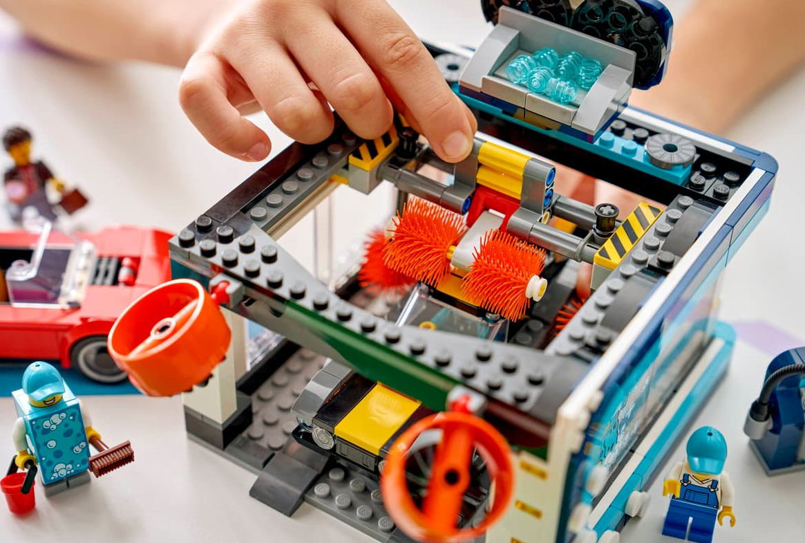 Kinder bauen eine Lego-Waschanlage mit Autos und Figuren.