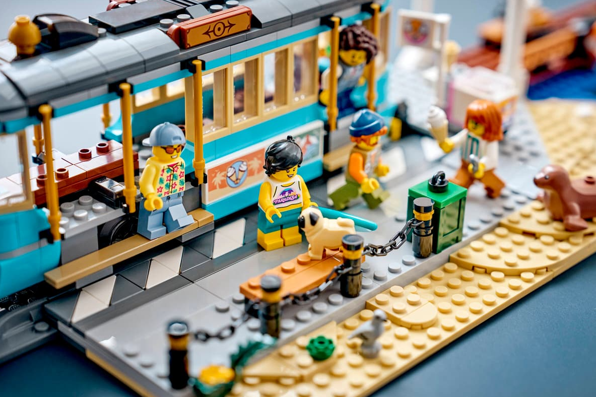 Lego-Szene: Menschen und ein Mops an einer Straßenbahn, Robbe und Vögel am Sandstrand.