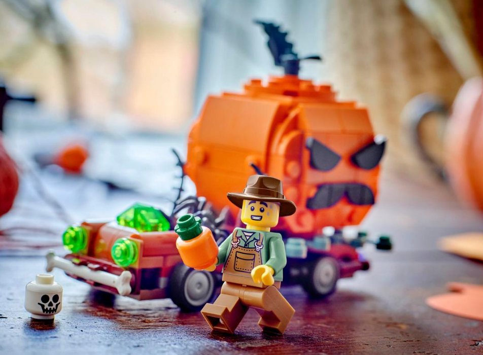 Ein Lego-Mann mit Hut hält eine Karotte vor einem Kürbis-Auto und einem Totenkopf.