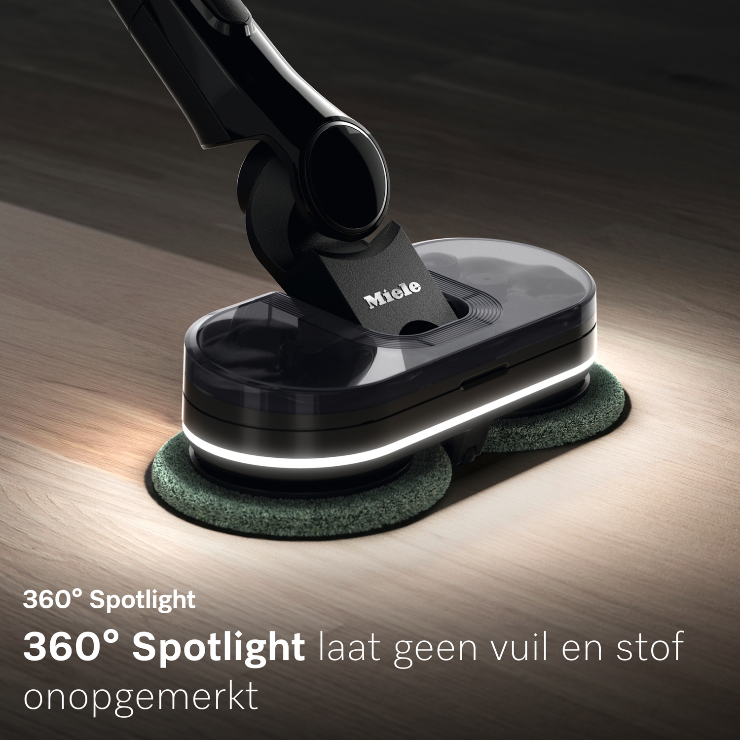 Zwarte Miele vloerreiniger met roterende borstels op een houten vloer.