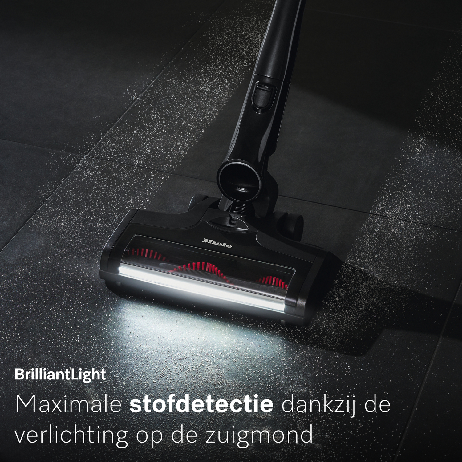 Een zwarte stofzuigerkop met licht reinigt stof van een donkere vloer.