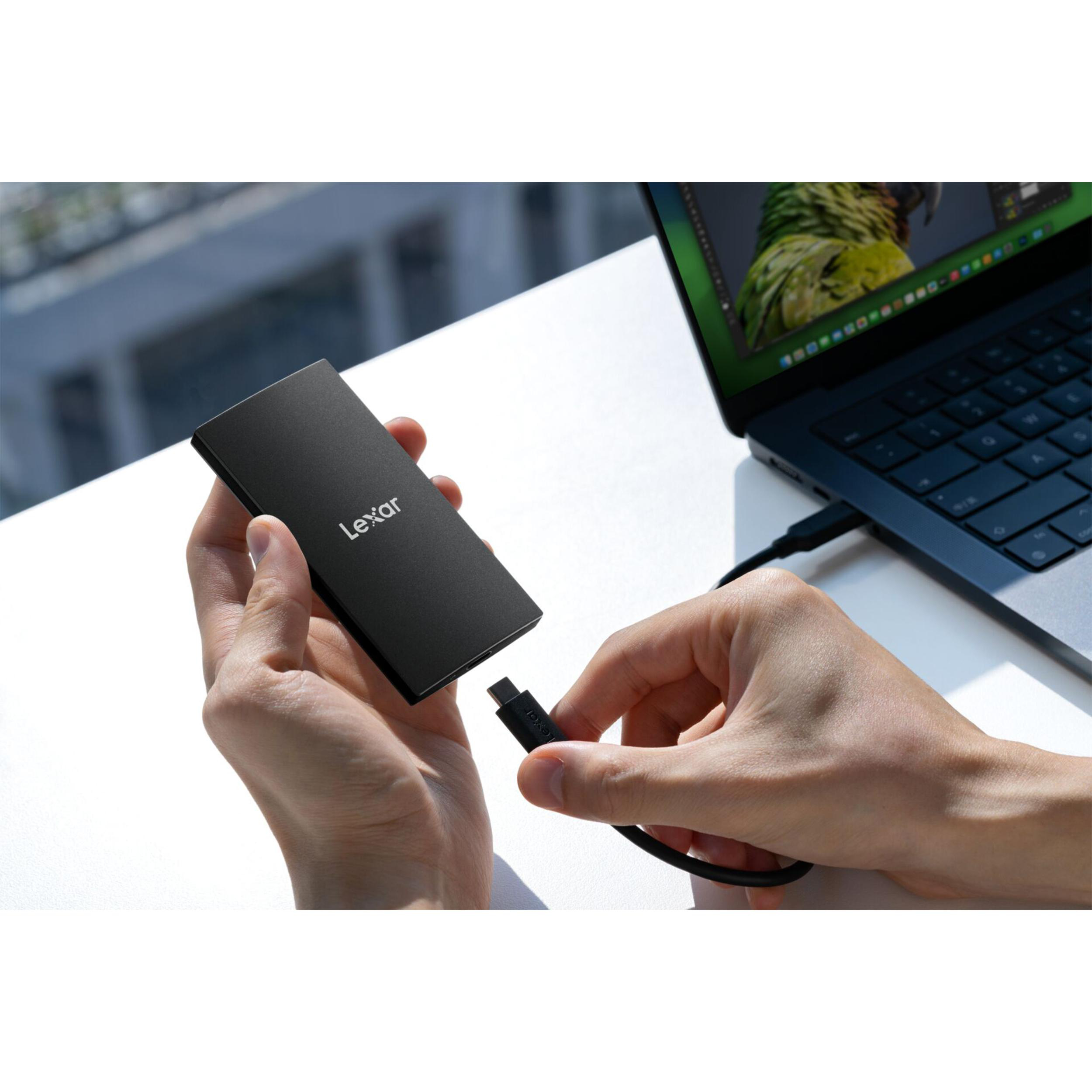 Schwarzes Lexar-Laufwerk wird mit einem USB-C-Kabel an einen Laptop angeschlossen.