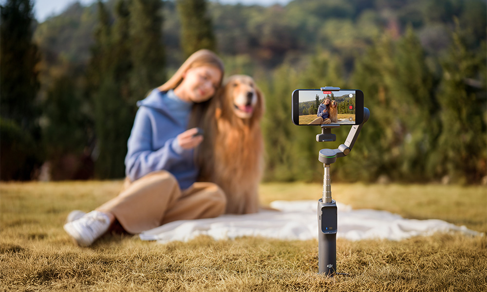 Kobieta i pies pozują do autorskiego filmu wideo na gimbalu na zewnątrz.