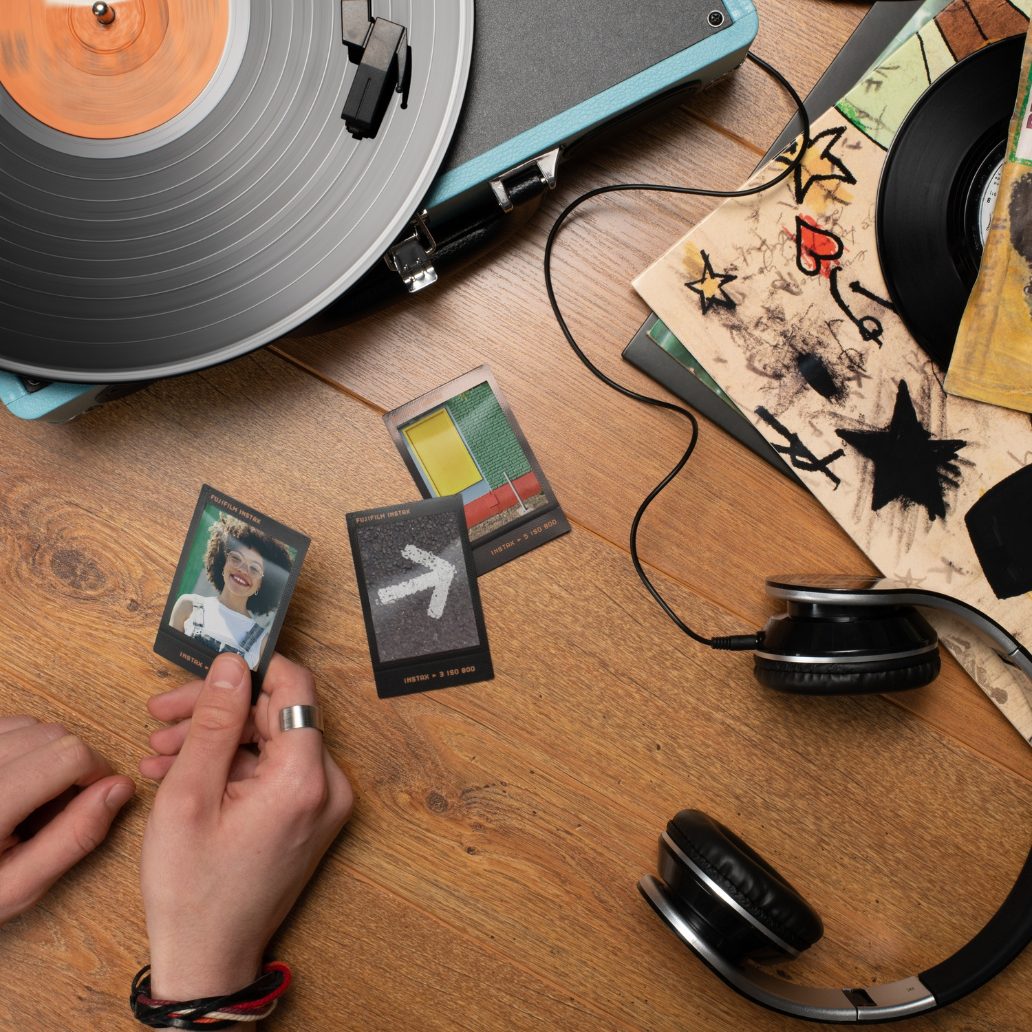 Platenspeler met vinylplaat, koptelefoon en instantfoto's op houten tafel.