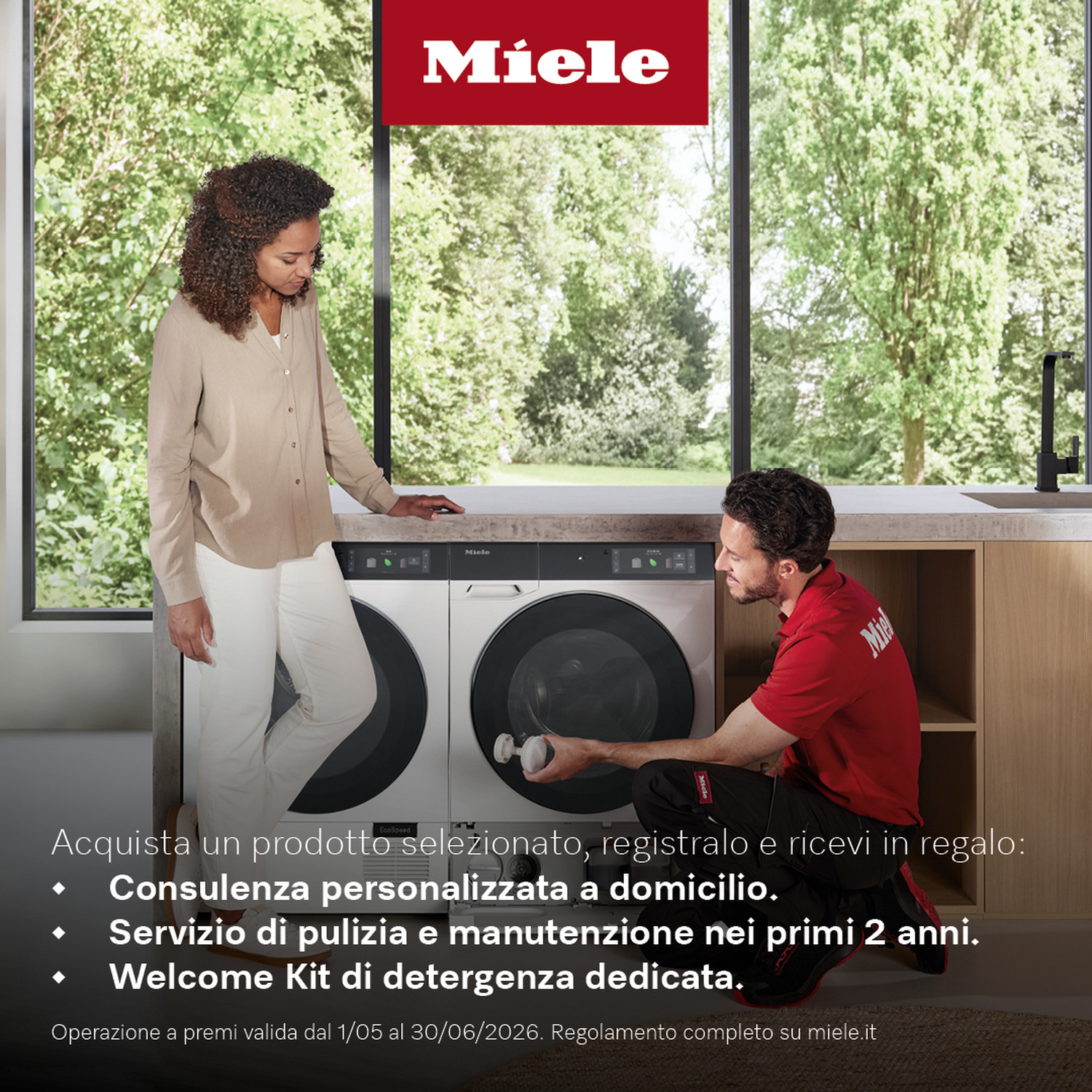 Donna e tecnico davanti a lavatrici Miele, finestra con alberi sullo sfondo.
