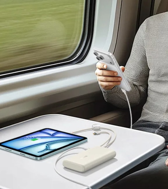 Tren yolcusu powerbank ile telefonunu ve tabletini şarj ediyor.