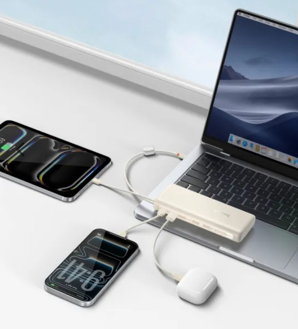 Bir dizüstü bilgisayar, iki akıllı telefon ve AirPods beyaz bir hub aracılığıyla şarj oluyor.