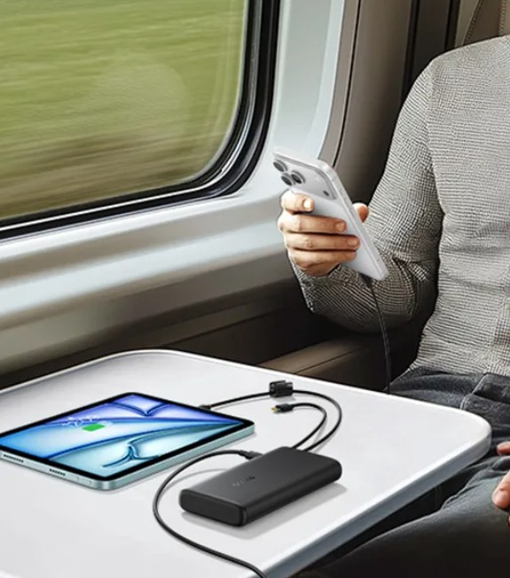 Tren yolcusu, powerbank ile tableti ve akıllı telefonu şarj ediyor.