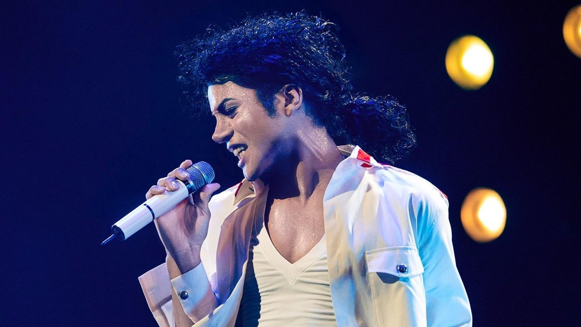Michael Jackson singt ins Mikrofon, trägt weiße Jacke und V-Ausschnitt-Shirt.