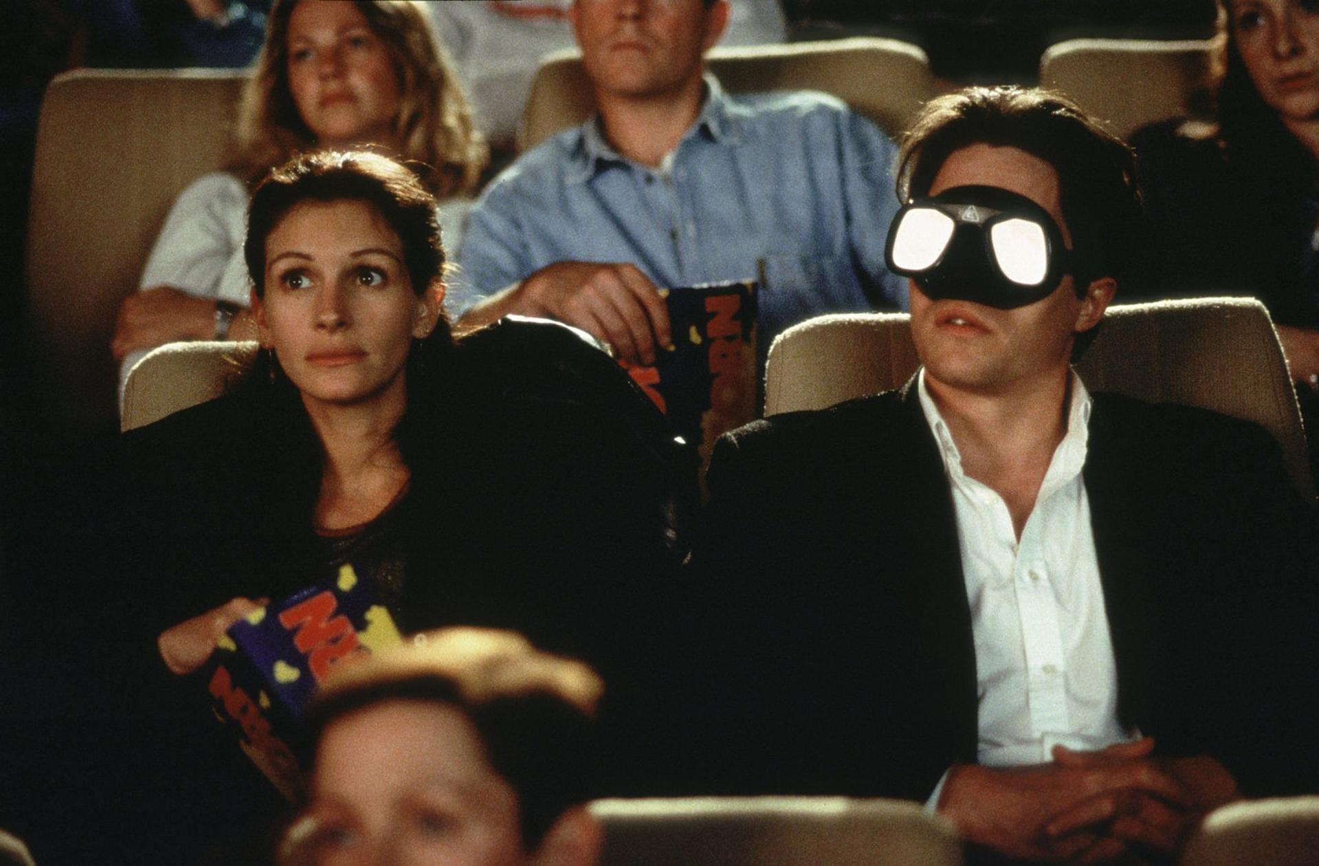 Frau und Mann im Kino mit 3D-Brille, sie hält eine Popcorn-Tüte.