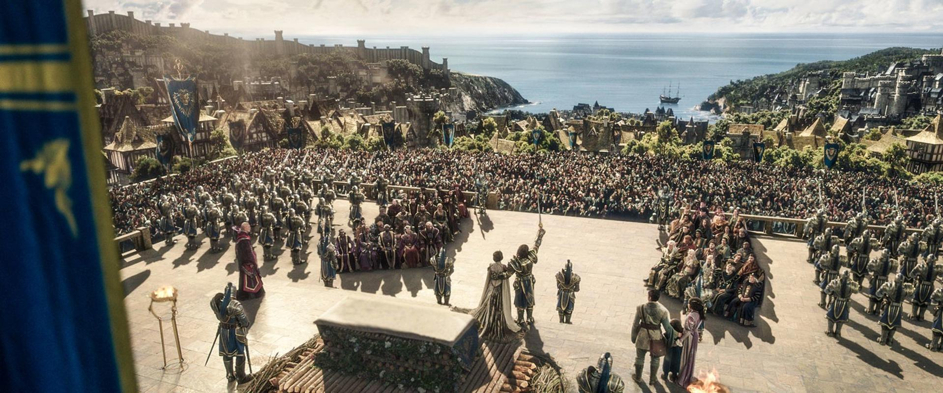 Ein großes mittelalterliches Stadtbild am Meer mit vielen Menschen und Soldaten.
