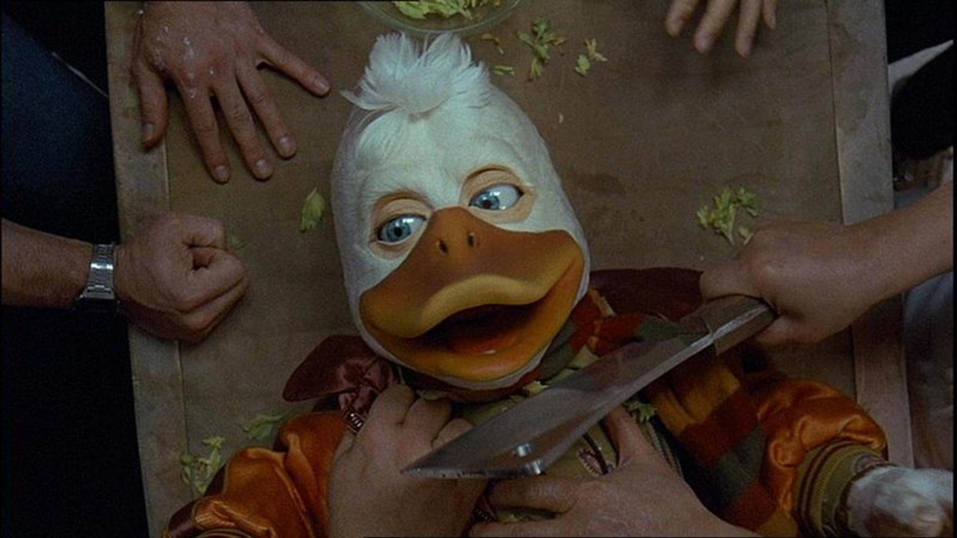 Eine Ente mit einem Messer wird von Händen gehalten, die auf einem Tisch liegen.