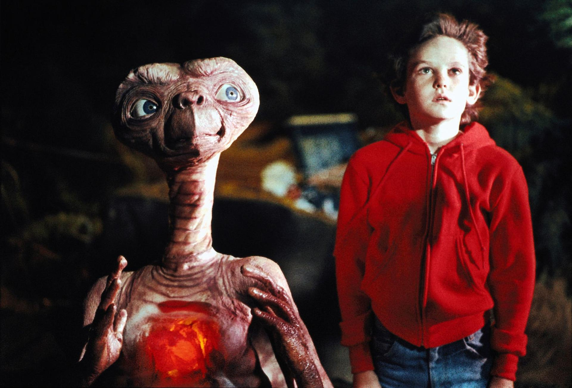 Ein Junge in einem roten Hoodie steht neben dem Außerirdischen E.T.