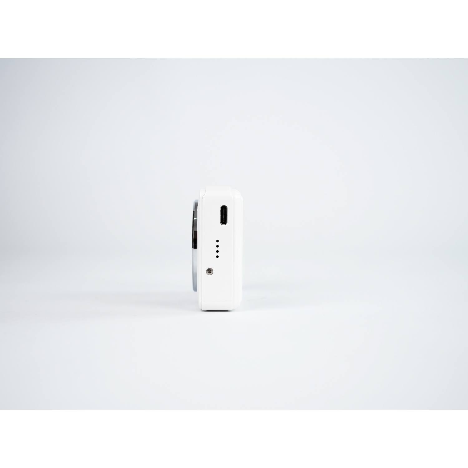 Una fotocamera bianca con porta USB-C e quattro spie di carica su sfondo grigio.
