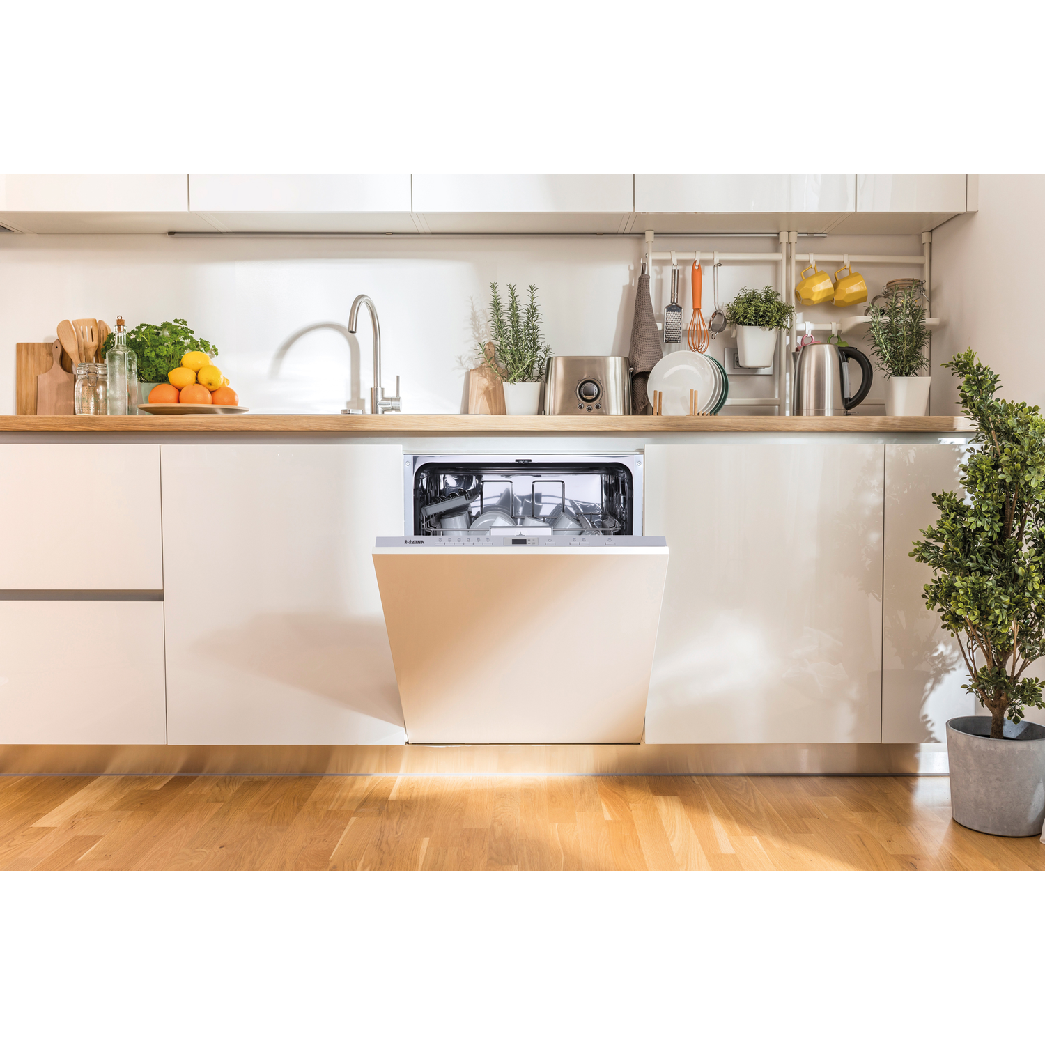 Een witte keuken met open vaatwasser, fruit en planten op het aanrecht.