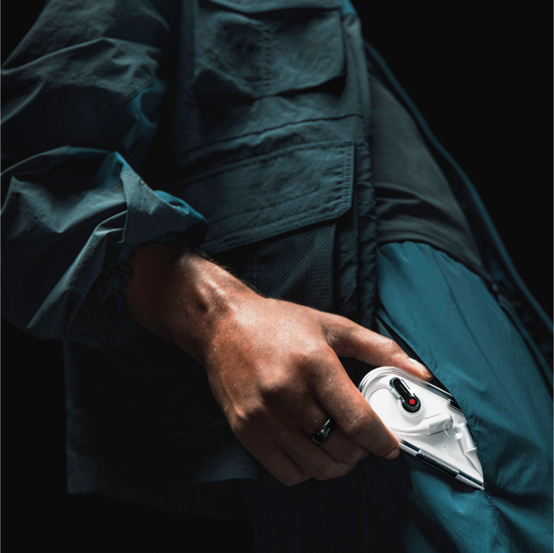 Eine Hand steckt weiße Ohrhörer in eine blaue Tasche.