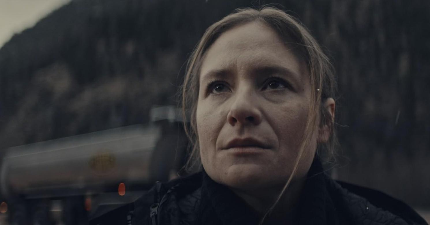 Eine Frau blickt nach oben, ein Tankwagen ist verschwommen im Hintergrund.