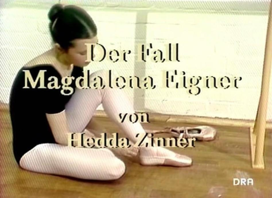 Eine Ballerina in schwarzem Anzug und rosa Strumpfhose sitzt auf dem Boden.