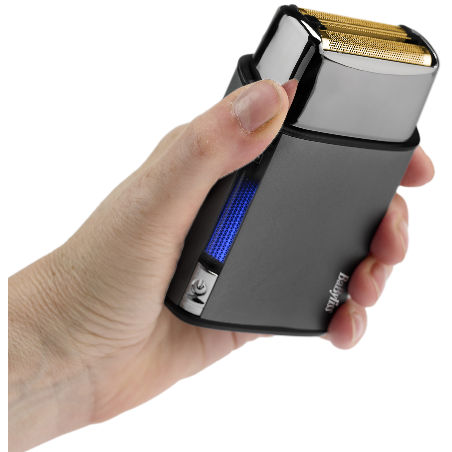 A hand holds a dark electric shaver with a gold foil head.