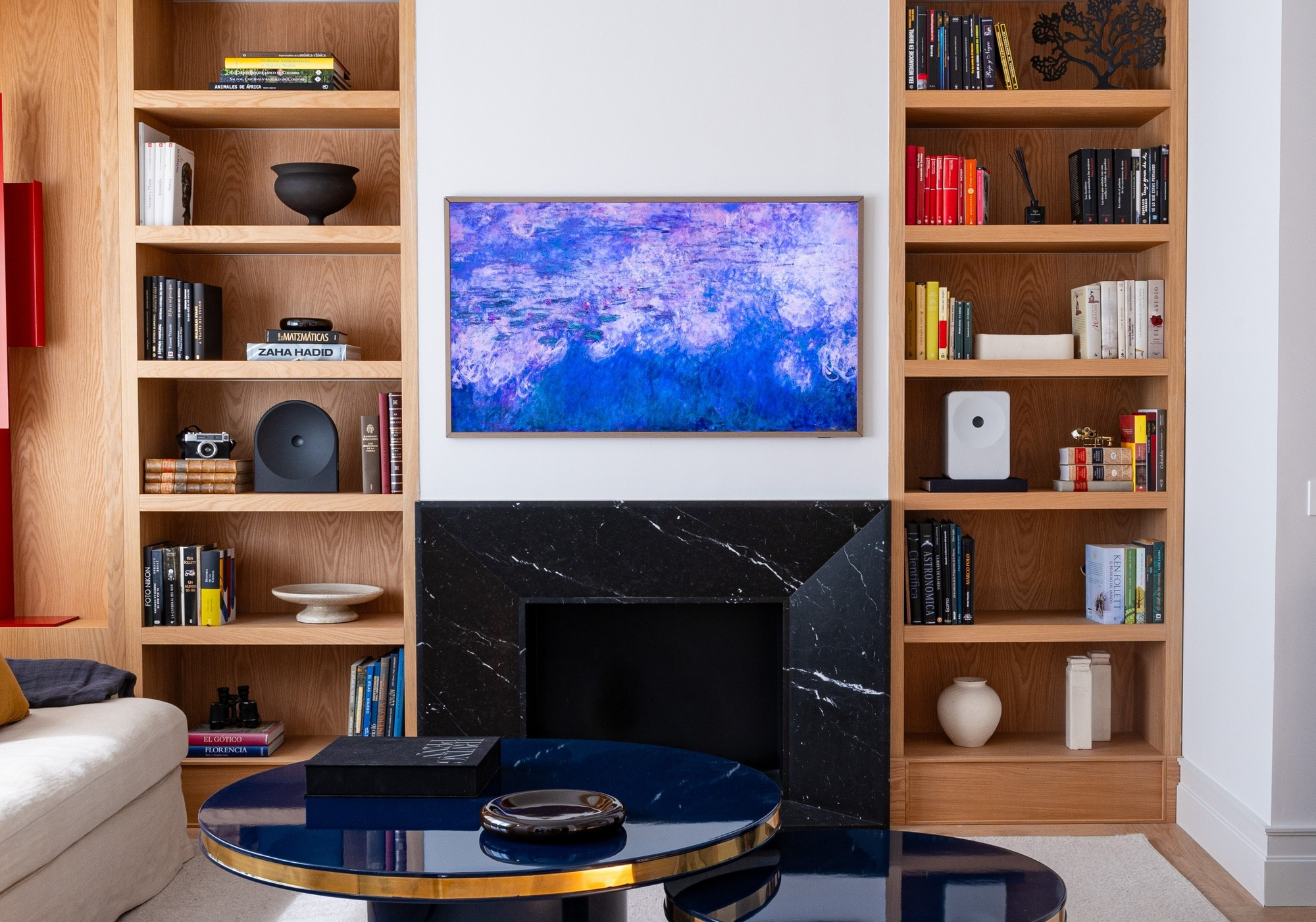 Una sala de estar con estanterías, chimenea y cuadro.
