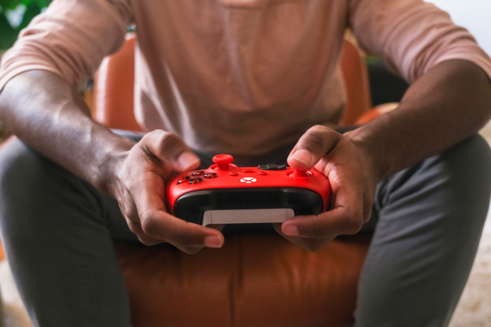 Una persona sostiene un mando rojo de Xbox en sus manos.