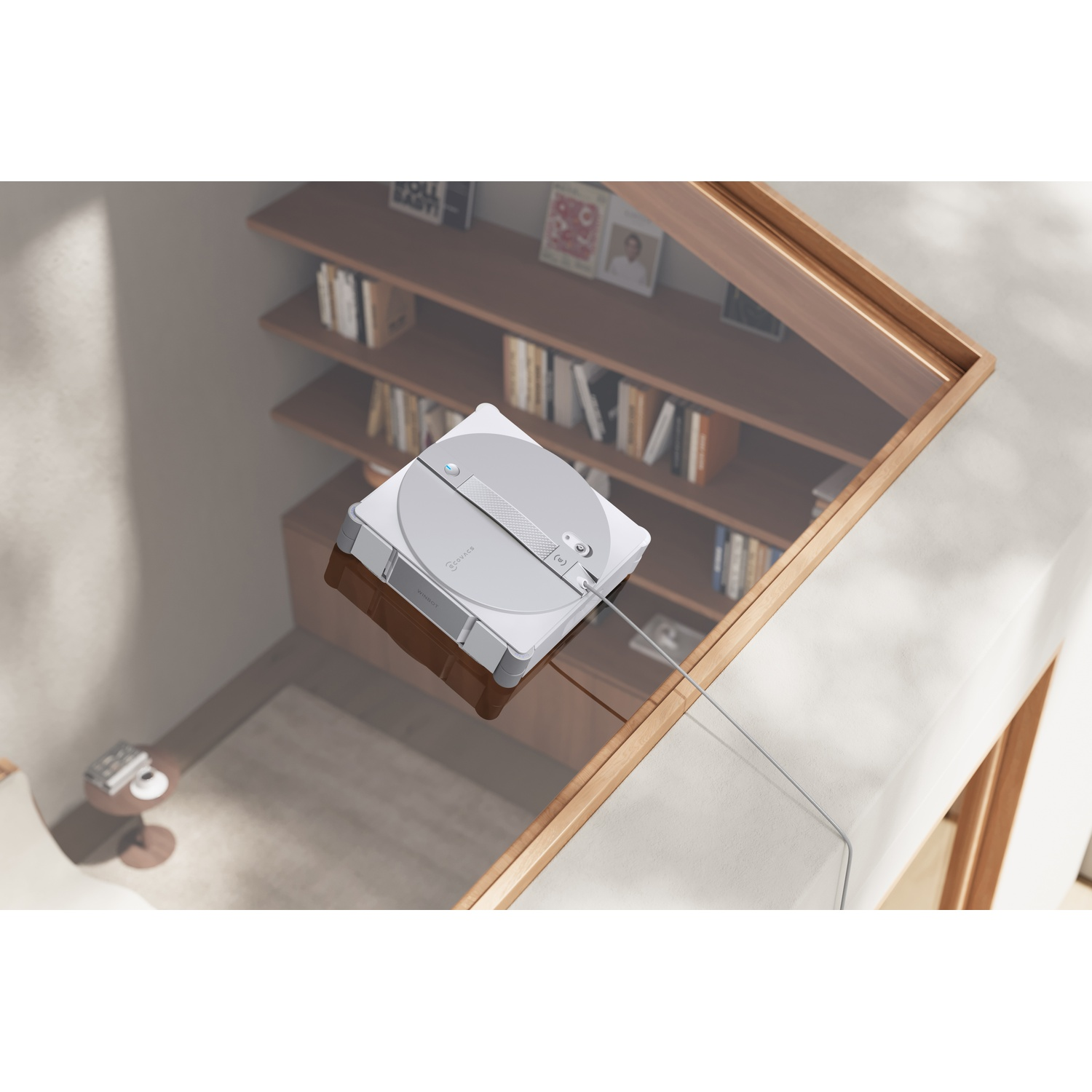 Un robot lavavetri bianco su una superficie di vetro, con una libreria sullo sfondo.