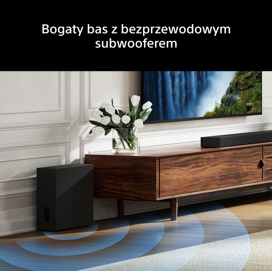 Czarny subwoofer obok drewnianej szafki z kwiatami i telewizorem.
