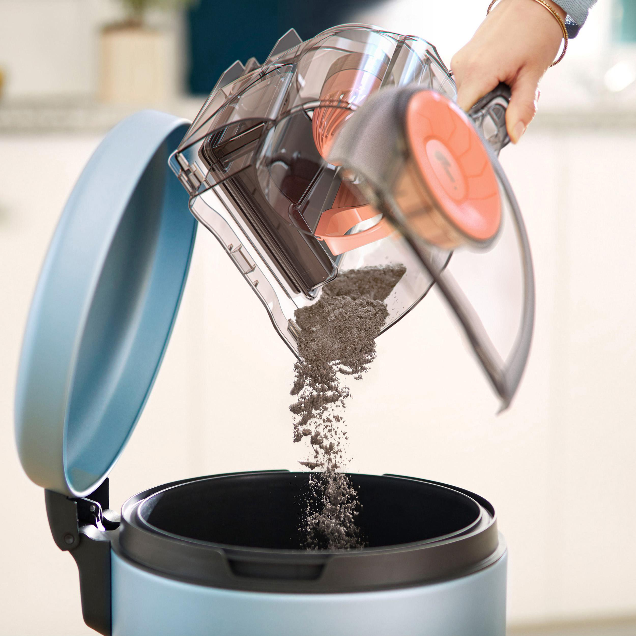 Staub wird aus einem durchsichtigen Behälter in einen blauen Mülleimer geleert.