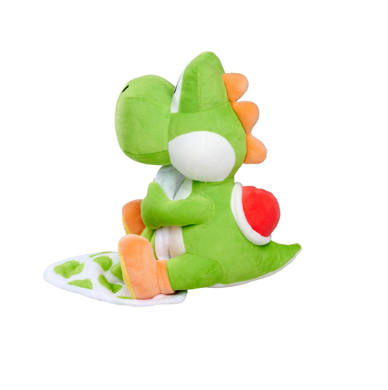 Ein grüner Yoshi-Plüsch auf einer weißen Decke mit grünen Flecken.