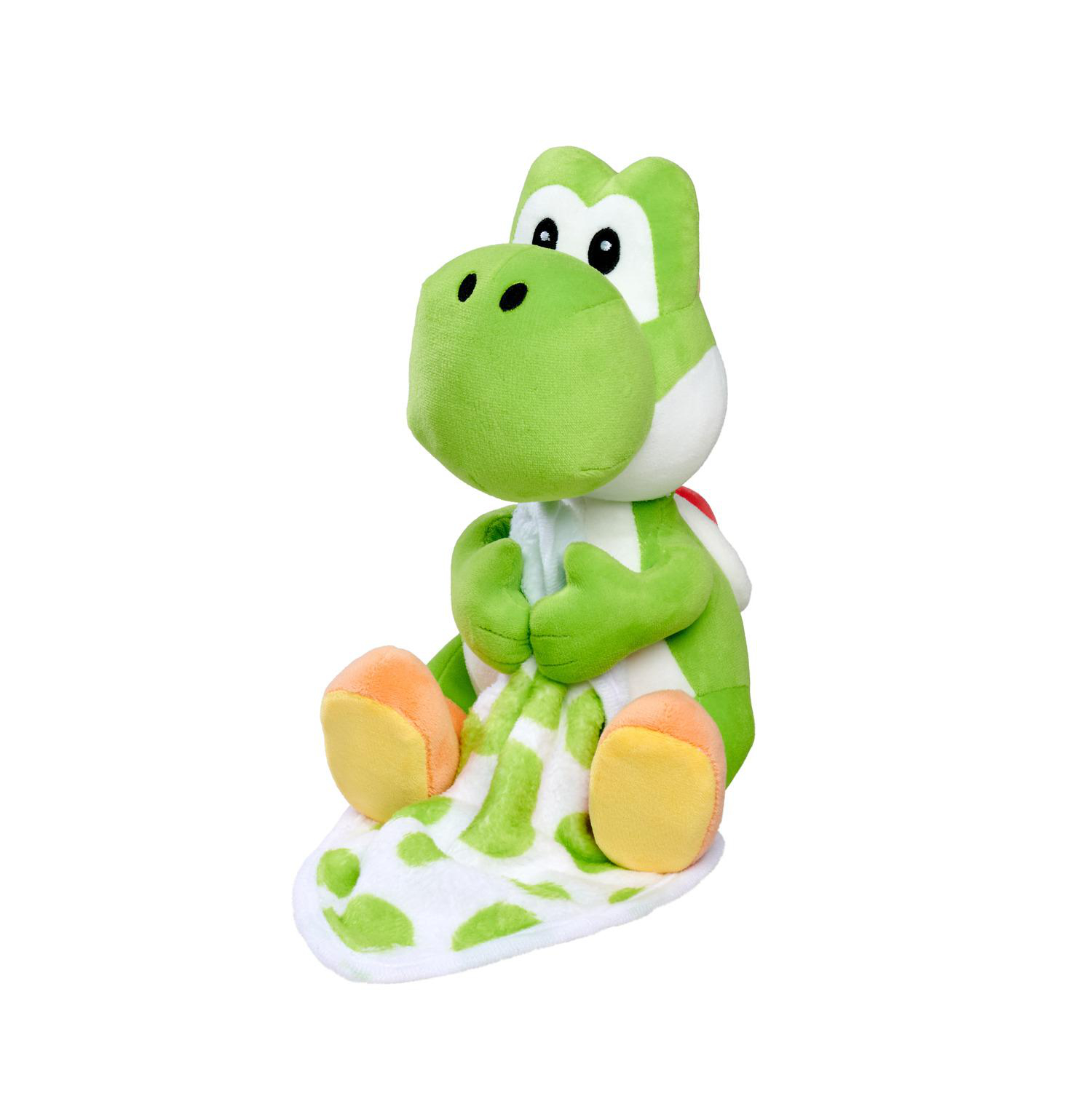 Ein grüner Yoshi-Plüschtier sitzt und hält eine Decke mit grünen Flecken.