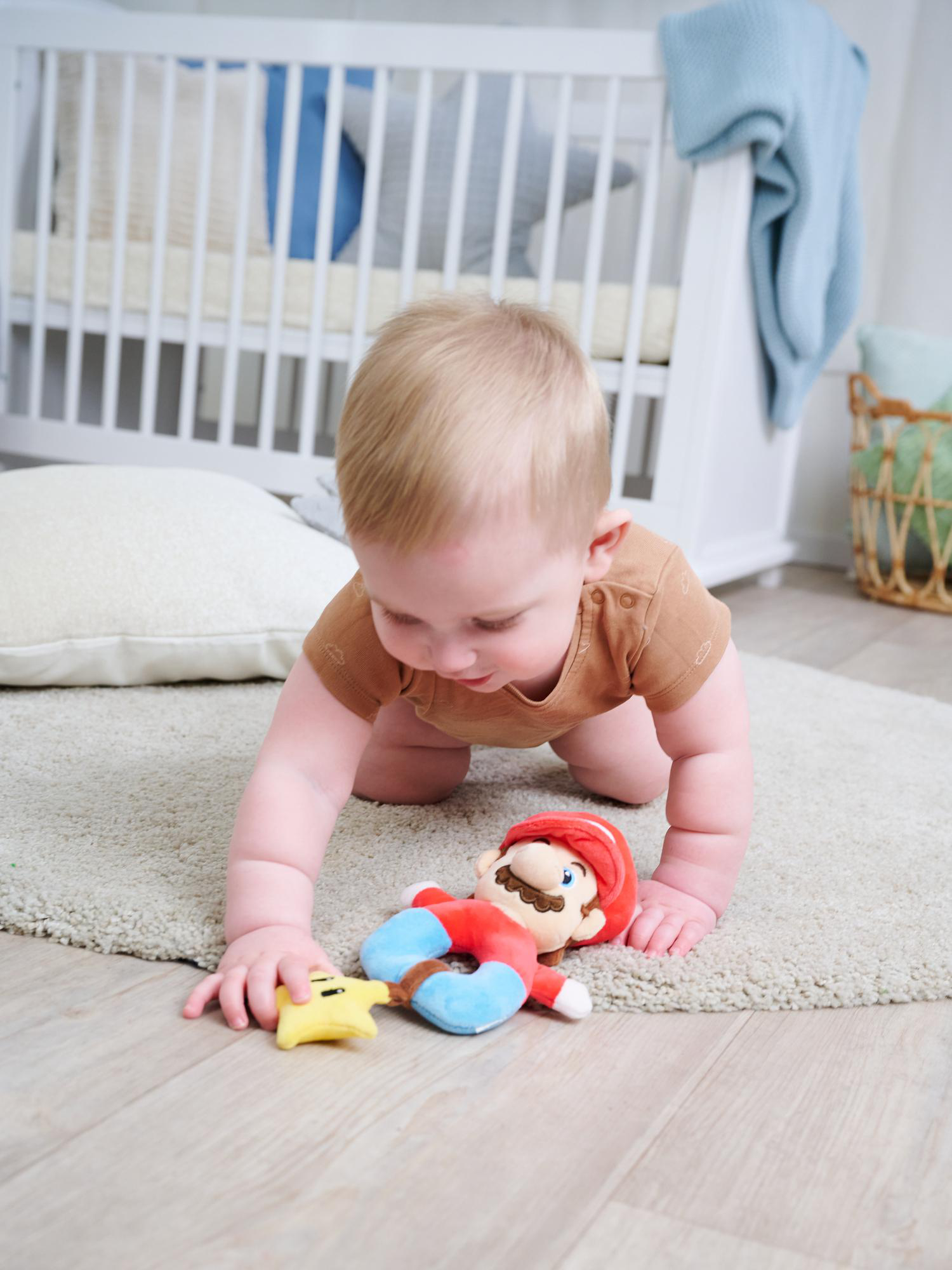 Ein Baby krabbelt auf einem Teppich und greift nach einem Mario-Spielzeug und einem Stern.