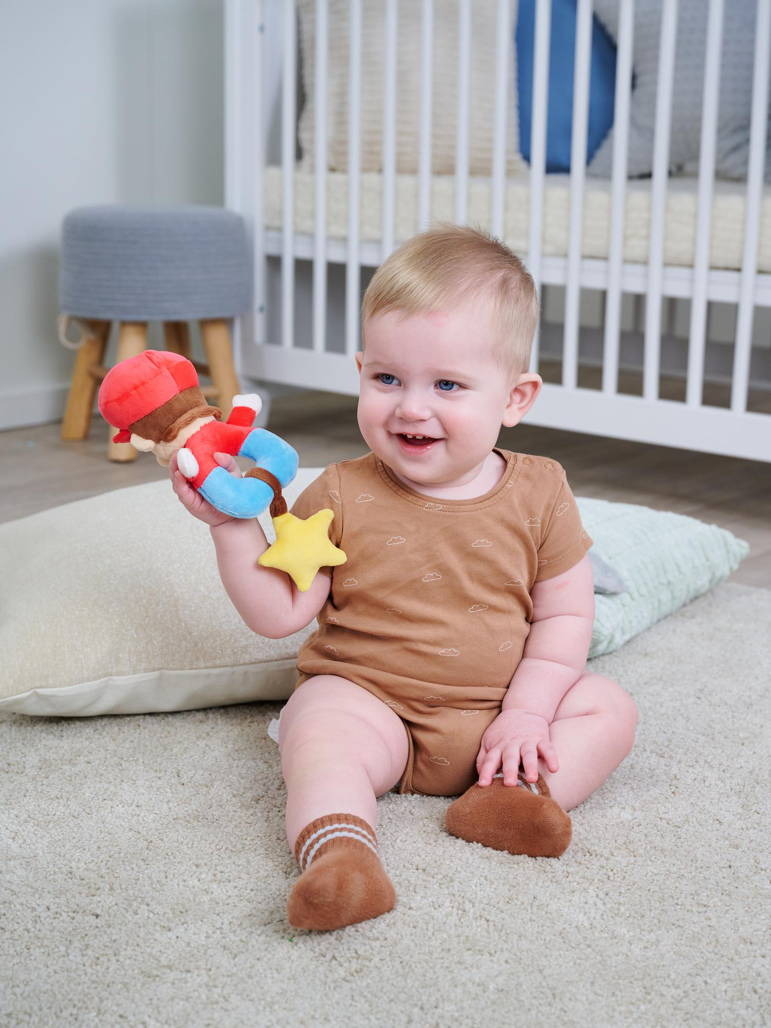Ein Baby sitzt auf einem Teppich und hält ein Stofftier.