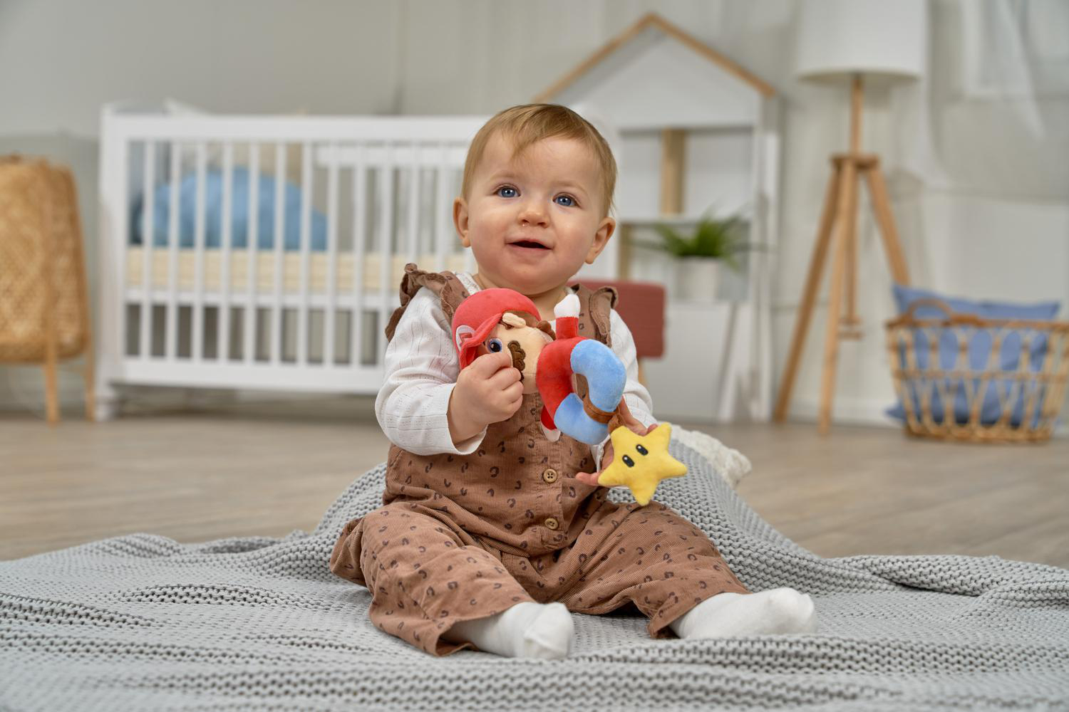 Ein Baby sitzt auf einer Decke und spielt mit Mario- und Stern-Spielzeug.
