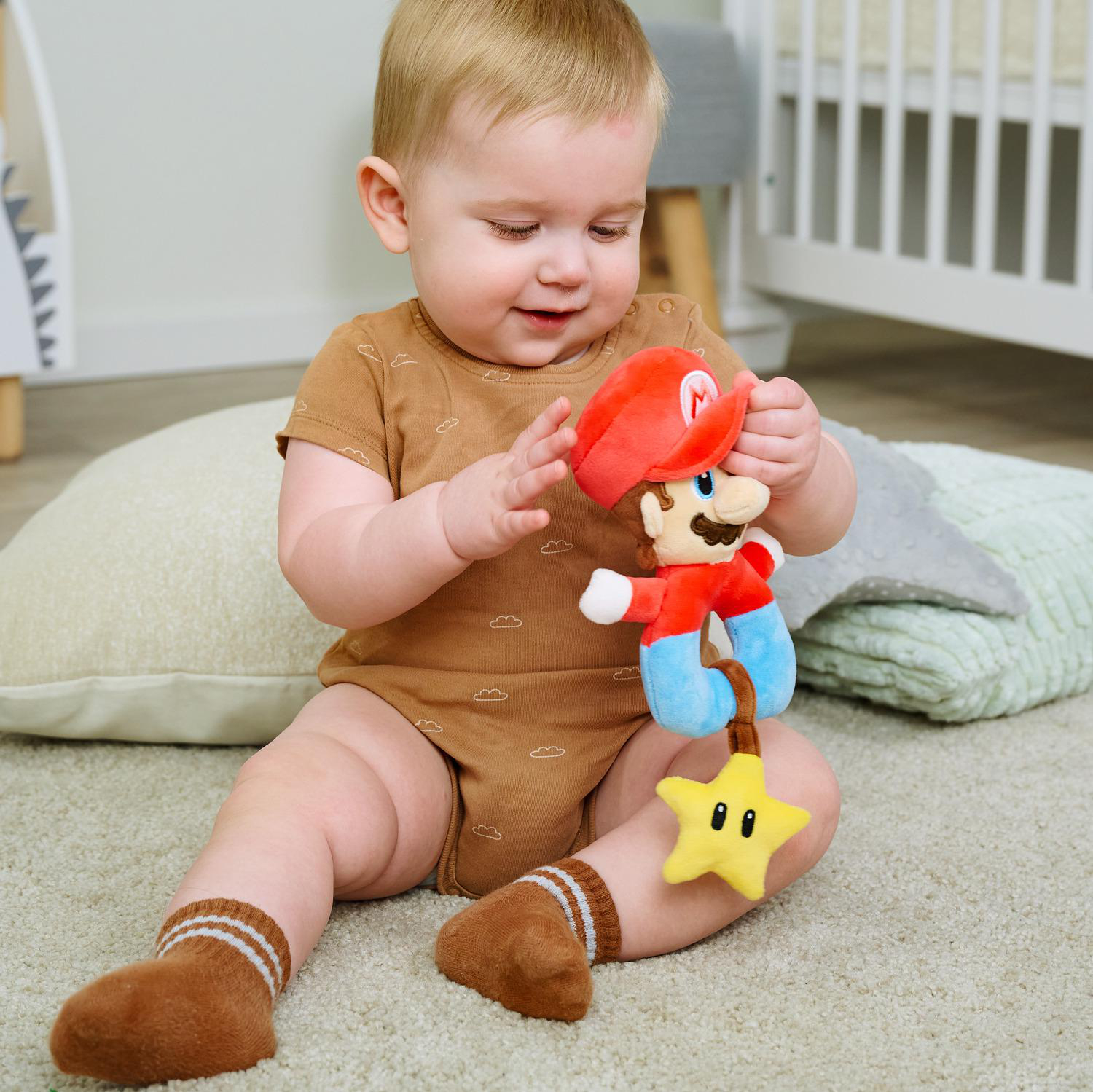 Ein Baby sitzt auf einem Teppich und spielt mit einer Mario-Puppe.