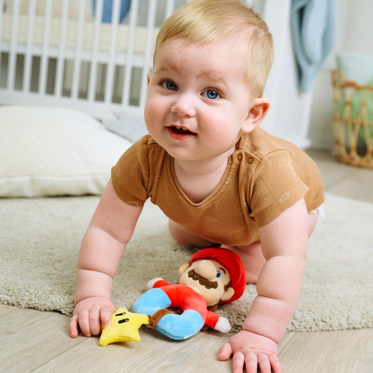 Ein Baby krabbelt auf einem Teppich mit einem Mario-Spielzeug und einem Sternspielzeug.
