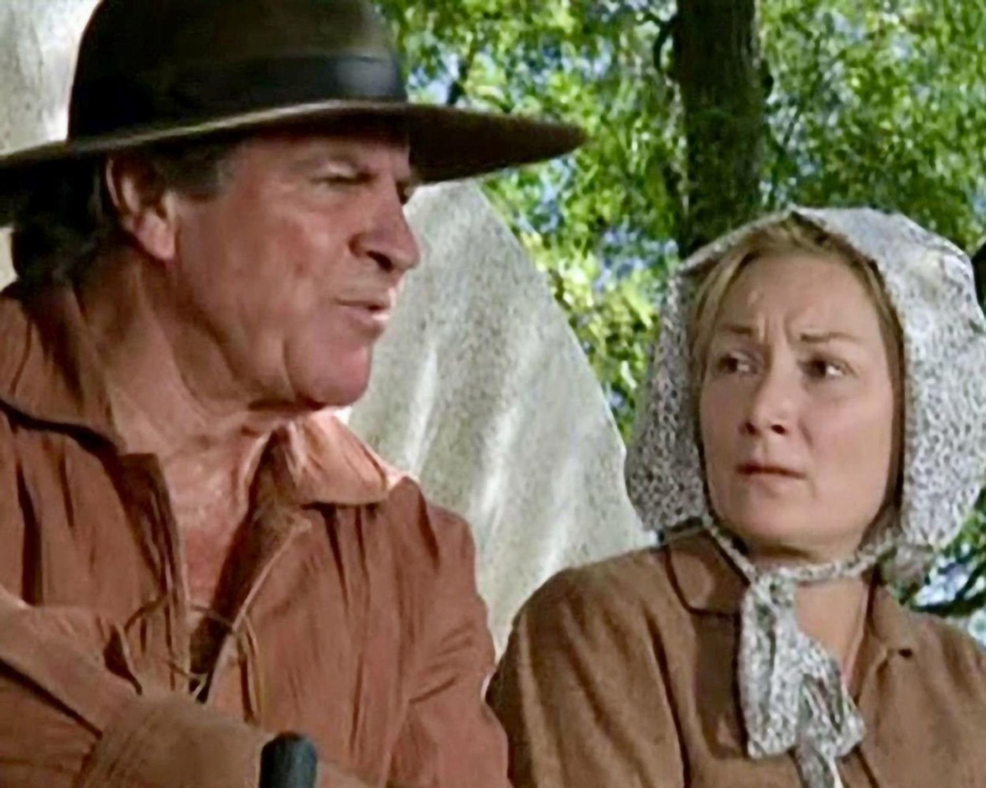 Ein Mann mit Hut und eine Frau mit Haube sprechen.