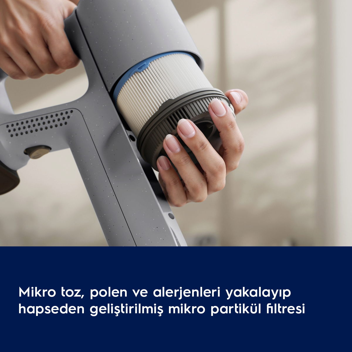 Bir el, mavi kenarlı gri bir elektrikli süpürge filtresi tutuyor.