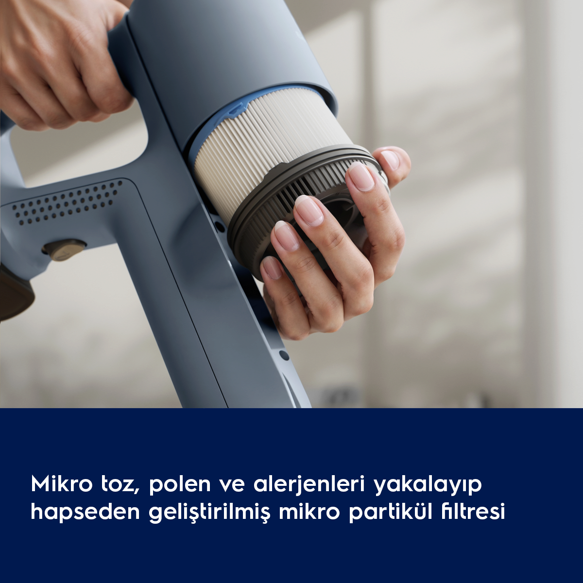Bir el mavi bir elektrikli süpürge tutuyor, filtre takıyor.