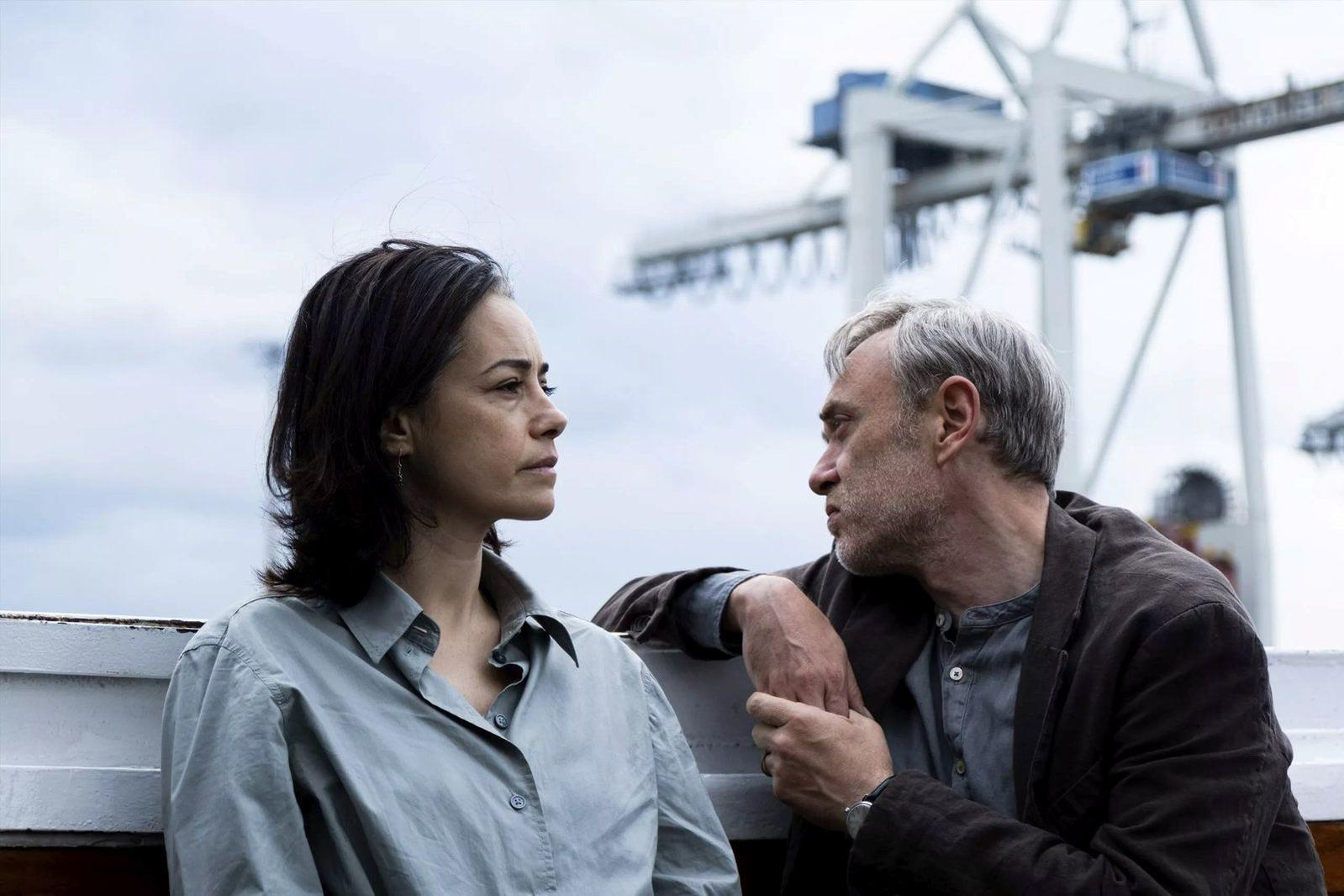 Mann und Frau auf einem Schiff vor Kränen