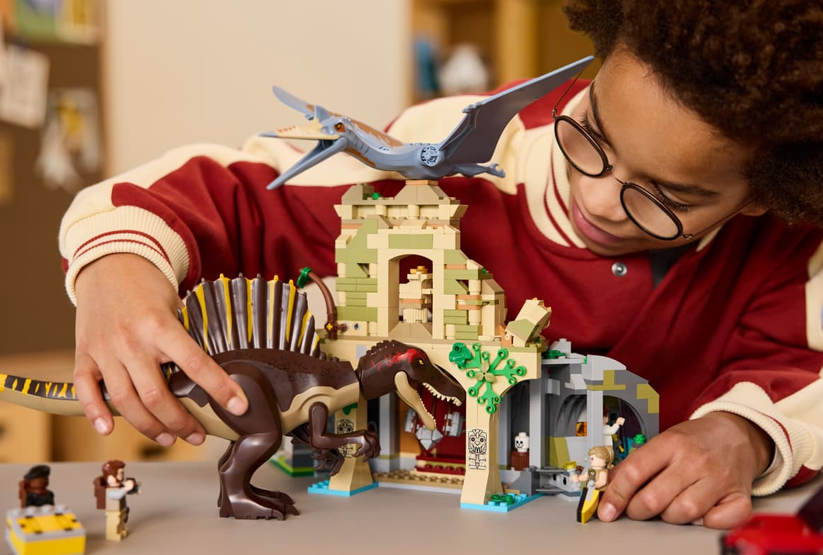 Ein Junge baut ein Lego-Dinosaurier-Set mit Spinosaurus und Pterodaktylus.