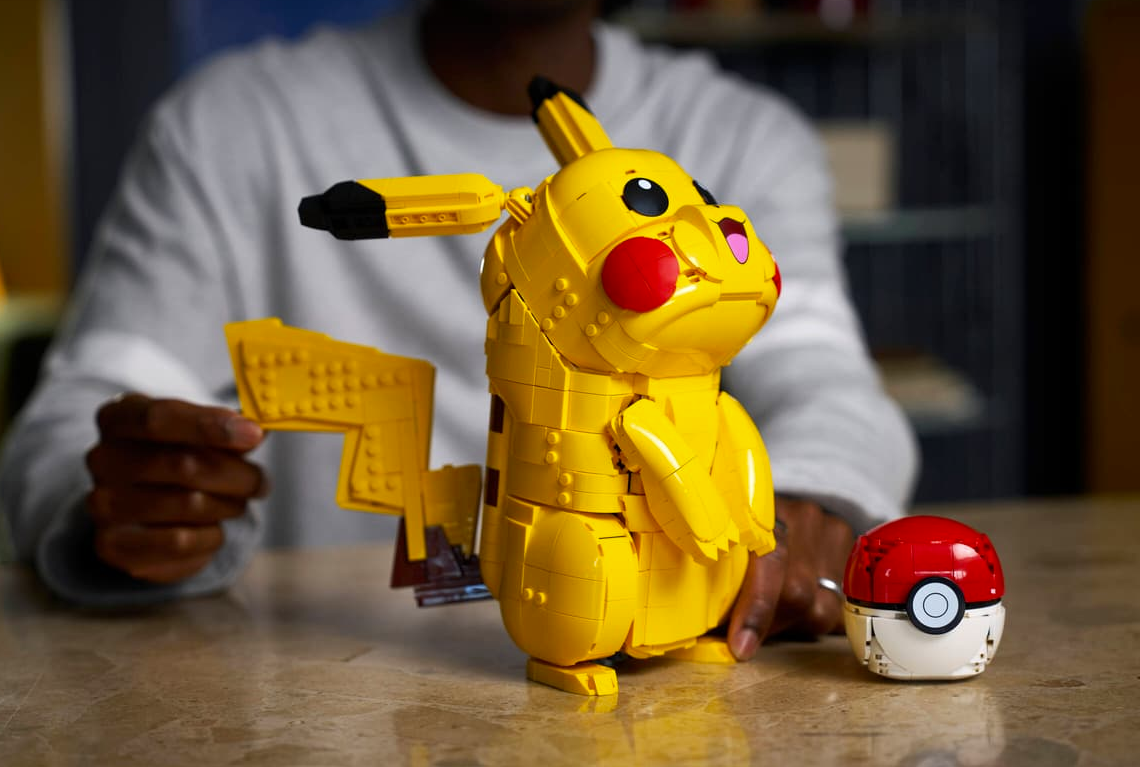 Ein gelber Lego-Pikachu-Aufbau mit Pokeball daneben, von einer Person gehalten.