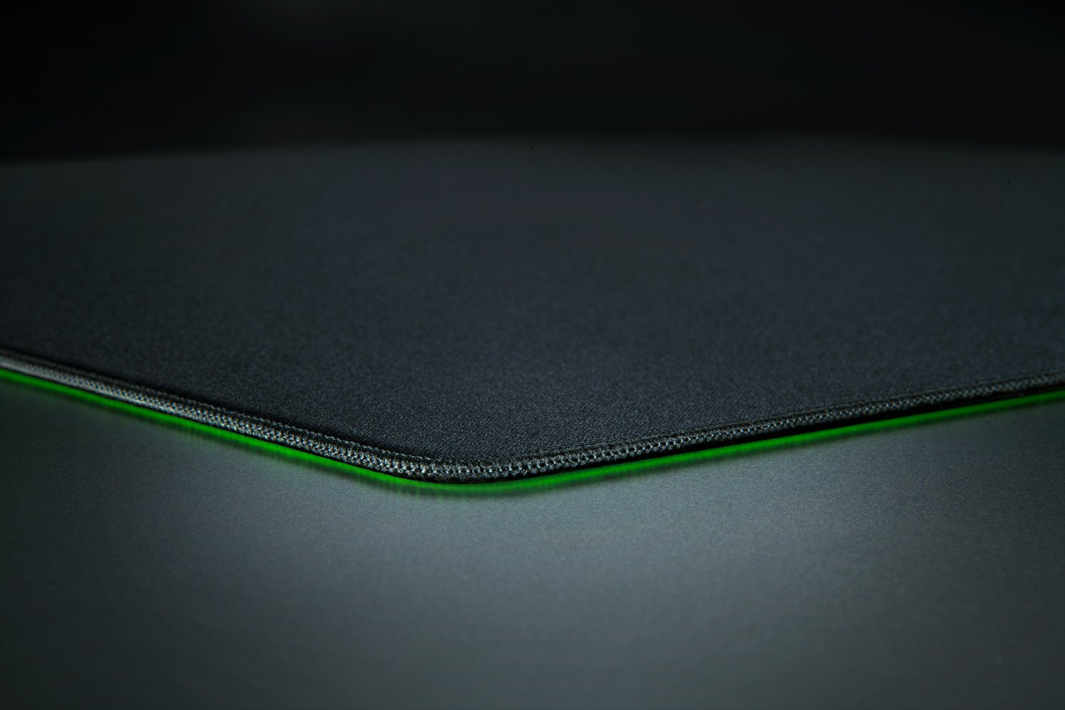 Un primer plano de una alfombrilla de ratón negra con iluminación de borde verde.