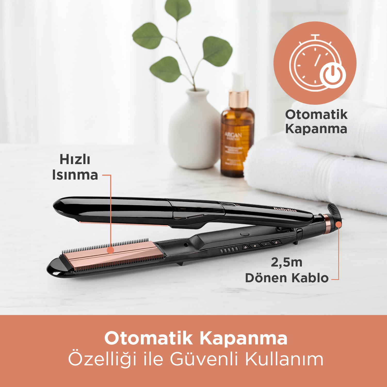 Rose gold plakalı siyah saç düzleştirici, yağ şişesi ve havlular.